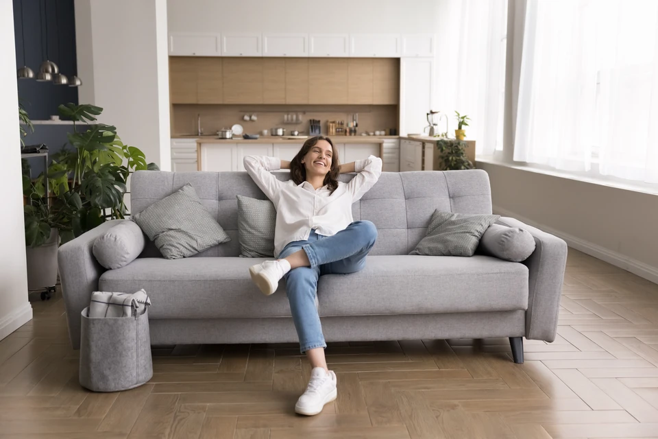 Installateur professionnel en salopette marron et gants bleus montant un conduit de ventilation noir dans les combles d'une habitation
