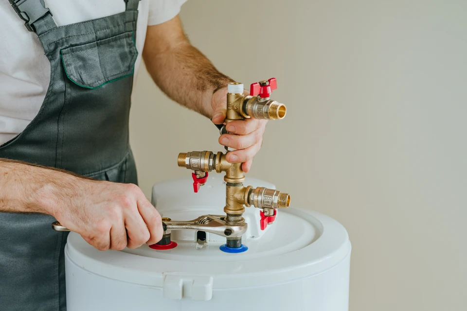 Technicien en uniforme bleu effectuant une intervention sur chauffe-eau domestique